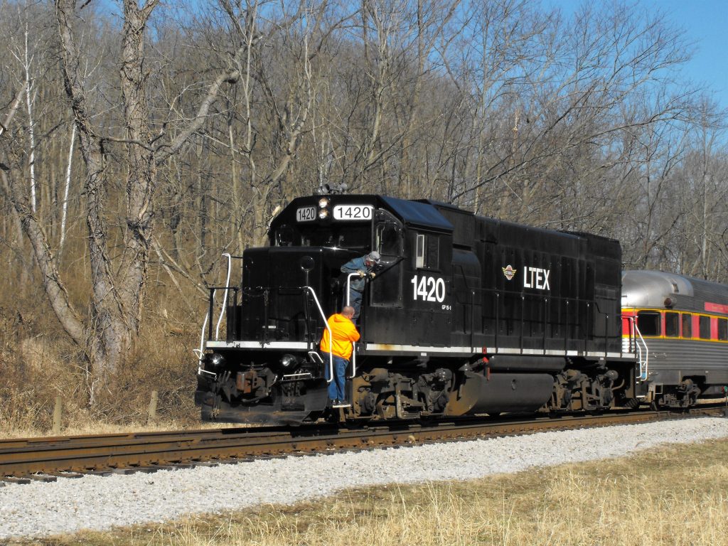 LTEX black locomotive, #1420 GP15 pulling passenger cars, two operators checking things out